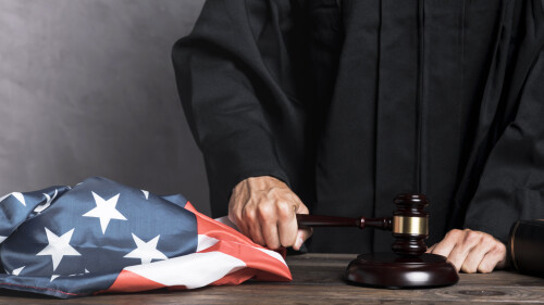 close-up-judge-with-flag-striking-gavel-2e0b780c0ef0b29b2.jpg